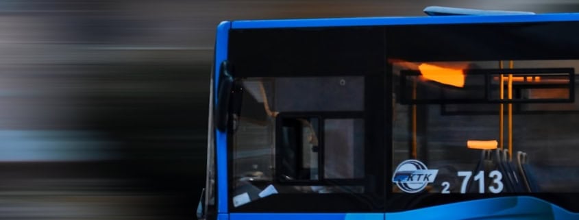 a blue bus driving down a street next to a tall building
