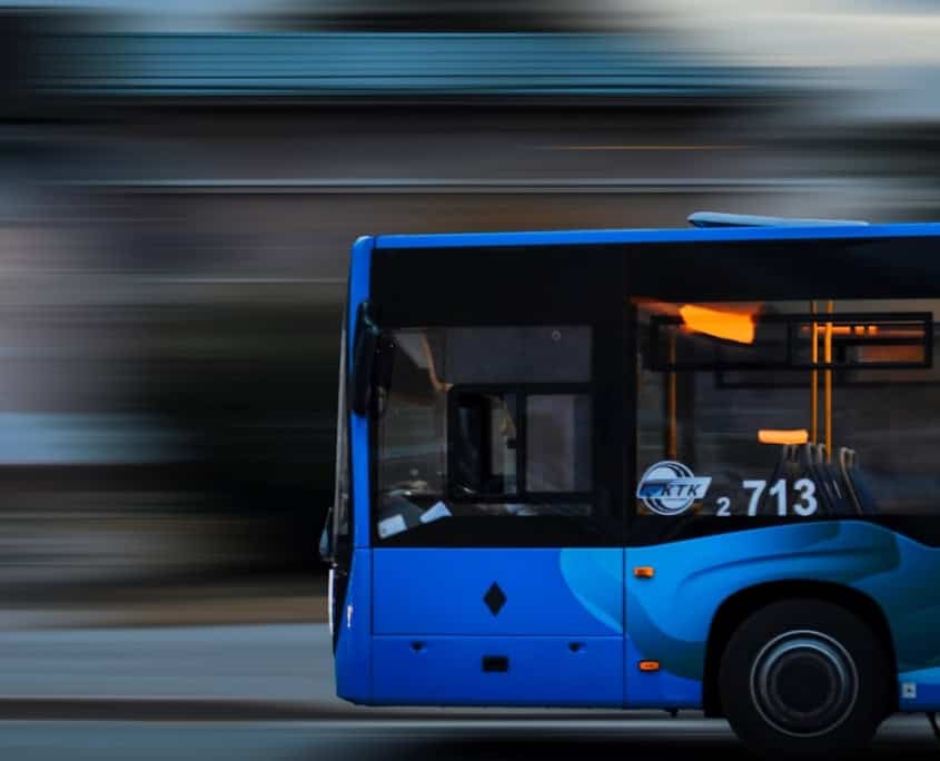 a blue bus driving down a street next to a tall building
