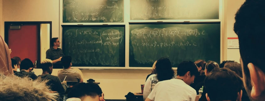 student sitting on chairs in front of chalkboard