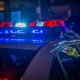 A police car with flashing red and blue emergency lights on a city street