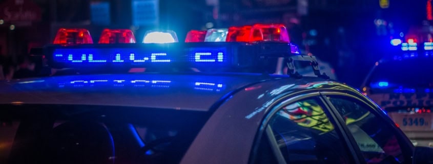 A police car with flashing red and blue emergency lights on a city street